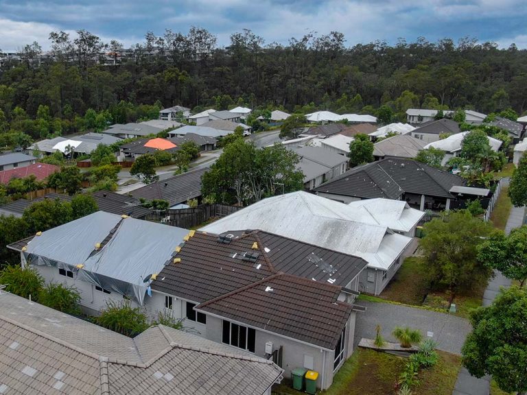 Aerial view of a residential area showing storm damage on the roof of a property.