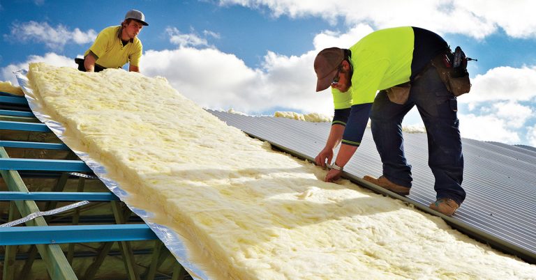 Roofers installing insulation on a metal roof.