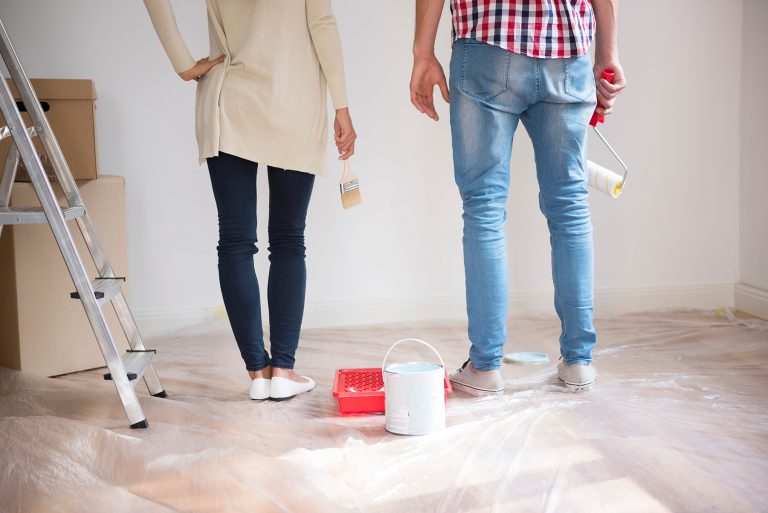 Couple holding supplies ready to paint a wall as part of a home renovation.