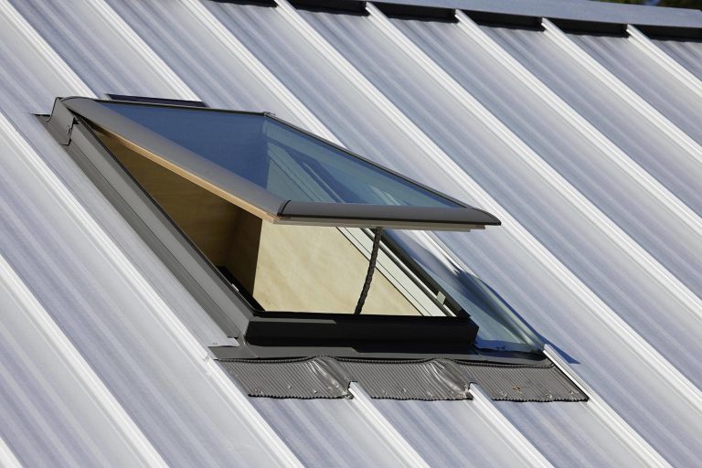 A closeup of an open skylight on a metal roof