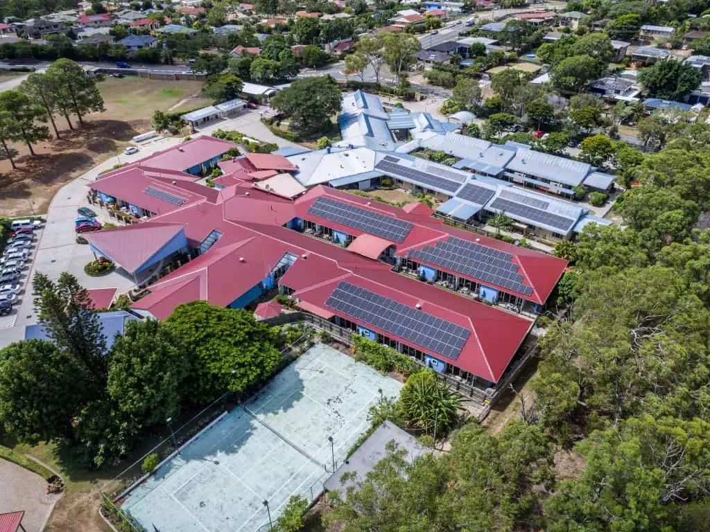 Red metal roof on a large commercial building with solar panels on the roof